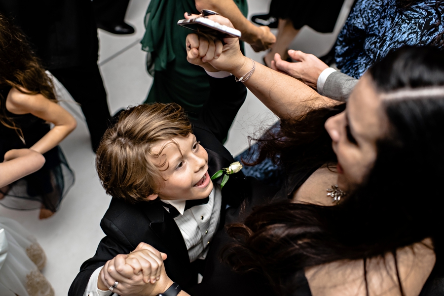 Wedding guests dancing with the ring bearer at the reception.